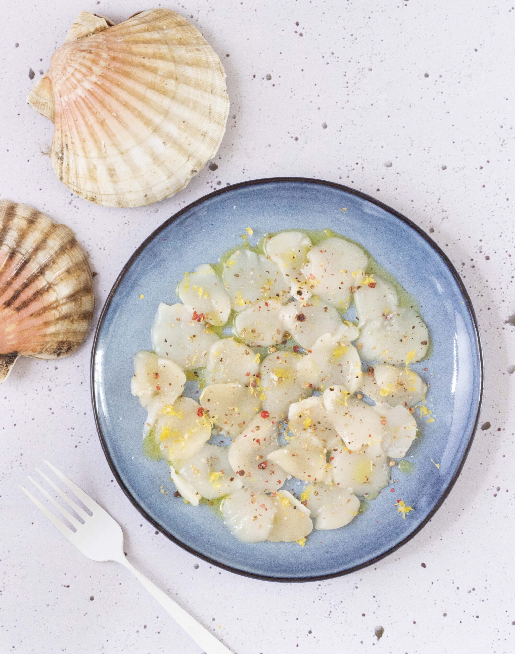 Recette du carpaccio de coquilles Saint-Jacques au citron, baies roses et coriandre